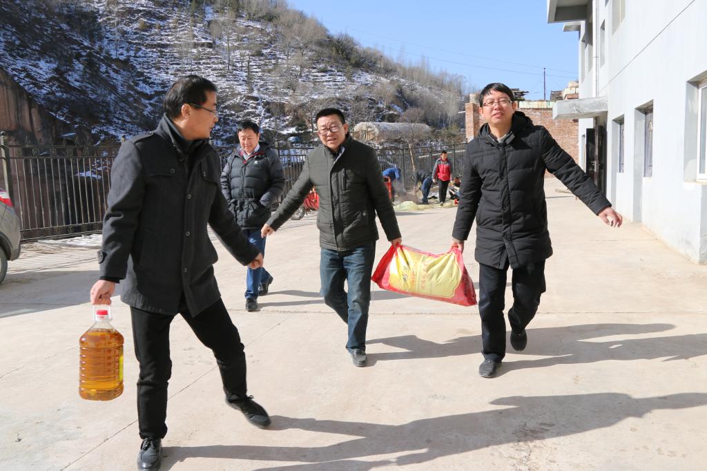 扶贫办主任冯学起与第一书记吴小军抬送慰问品